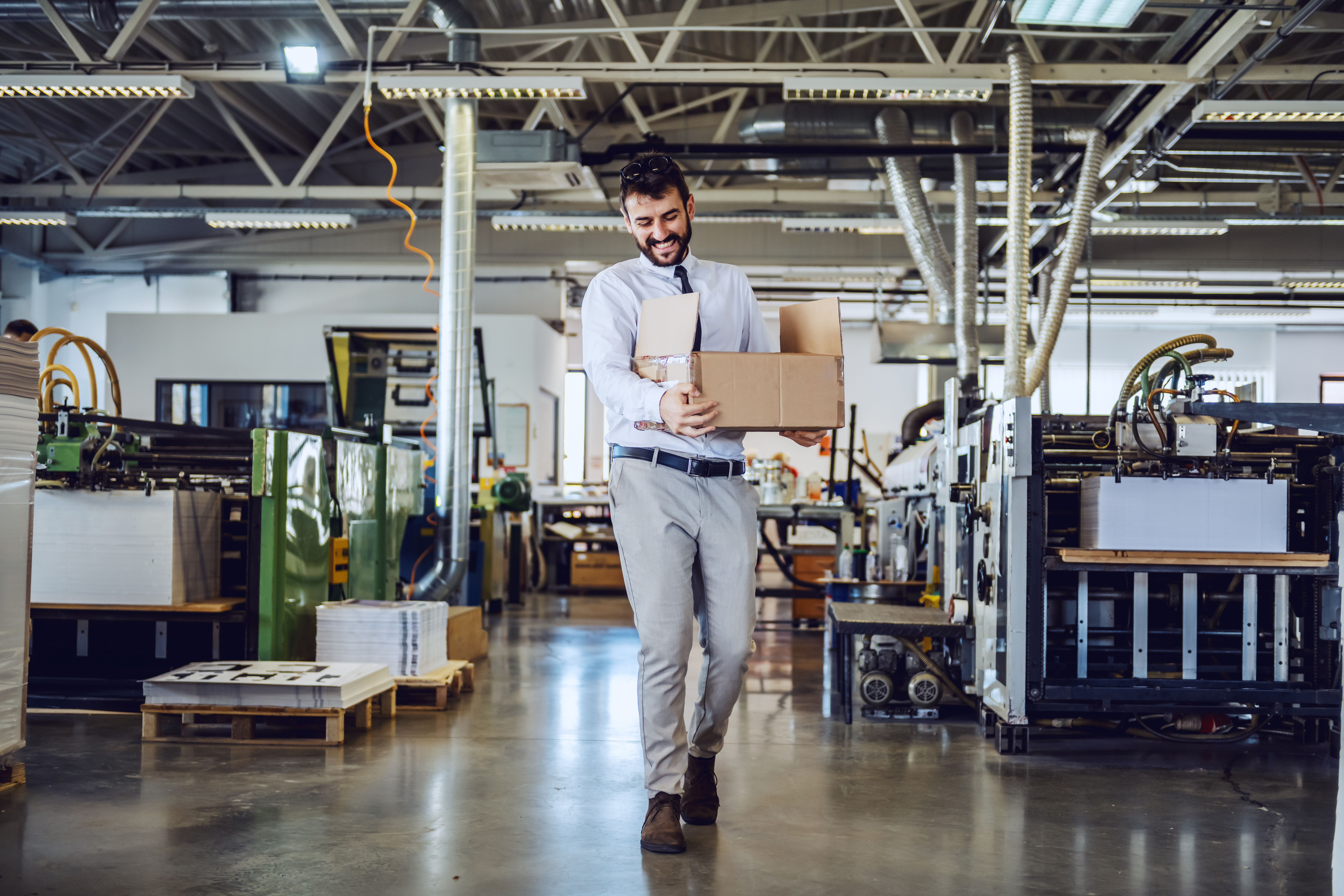 employee carrying box through warehouse wearing suit
