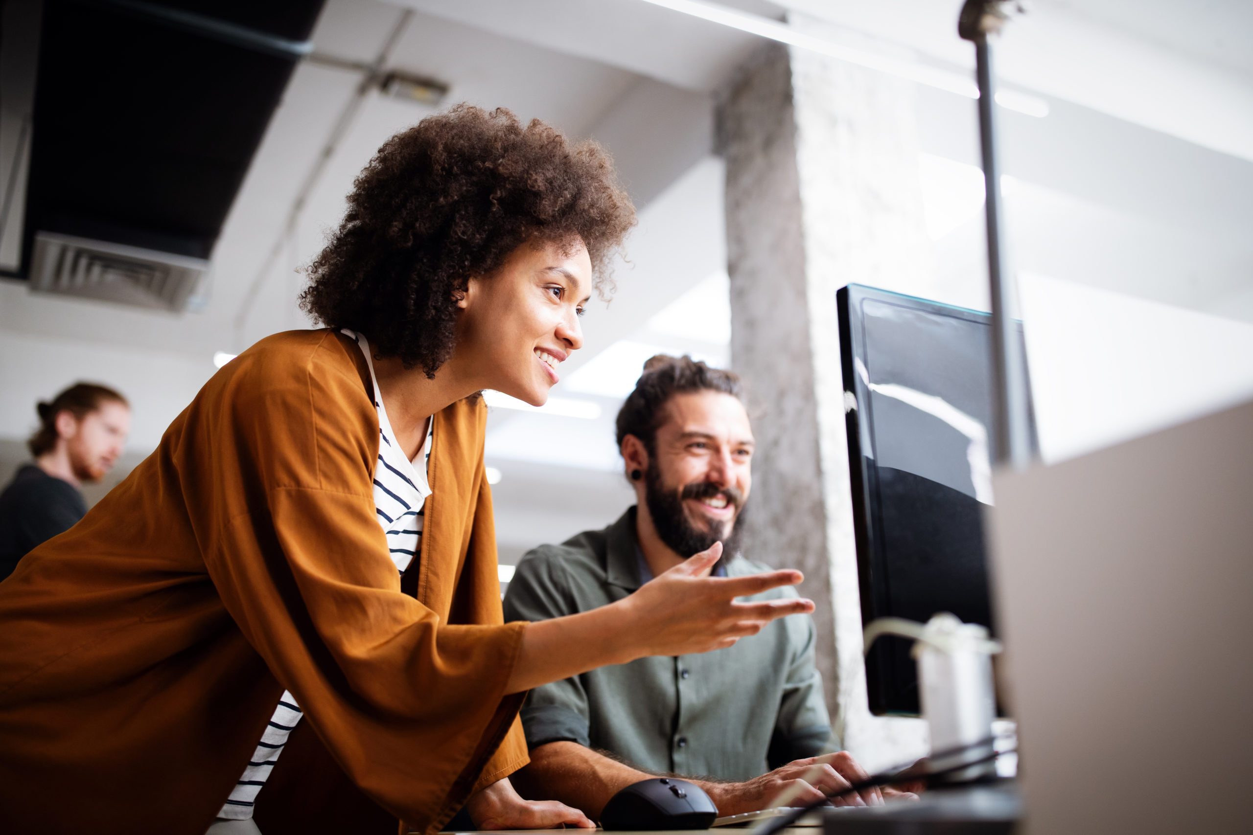Photo of woman and man in office looking at computer monitor smiling because of robotic process automation software