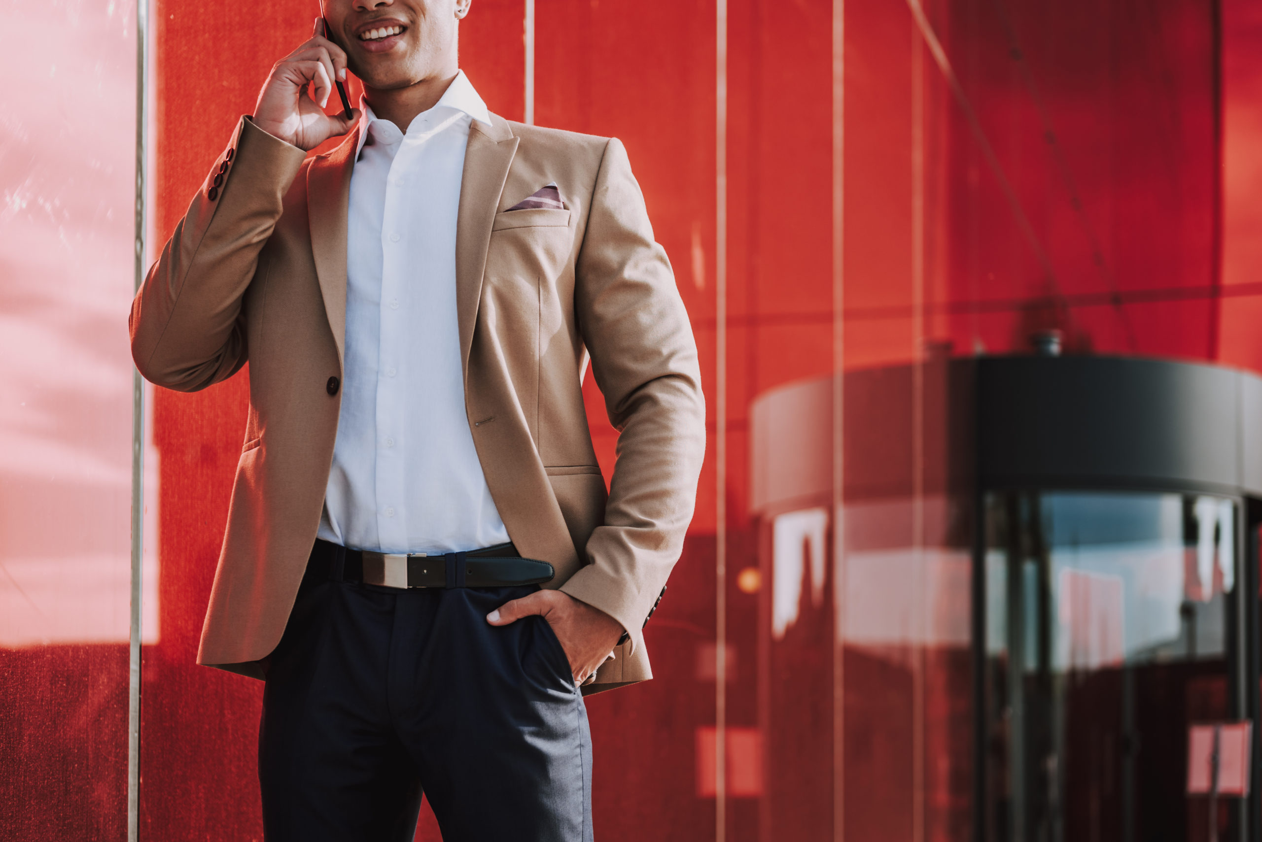 Photo of smiling businessman on phone outside building