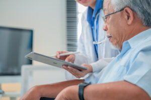 Asian healthcare professionals conduct medical consultations with senior patients using digital technology. Doctor examines elderly woman with stethoscope during comprehensive checkup
