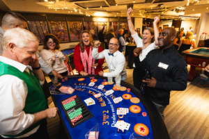Group of people excitedly playing blackjack at company fundraising gala
