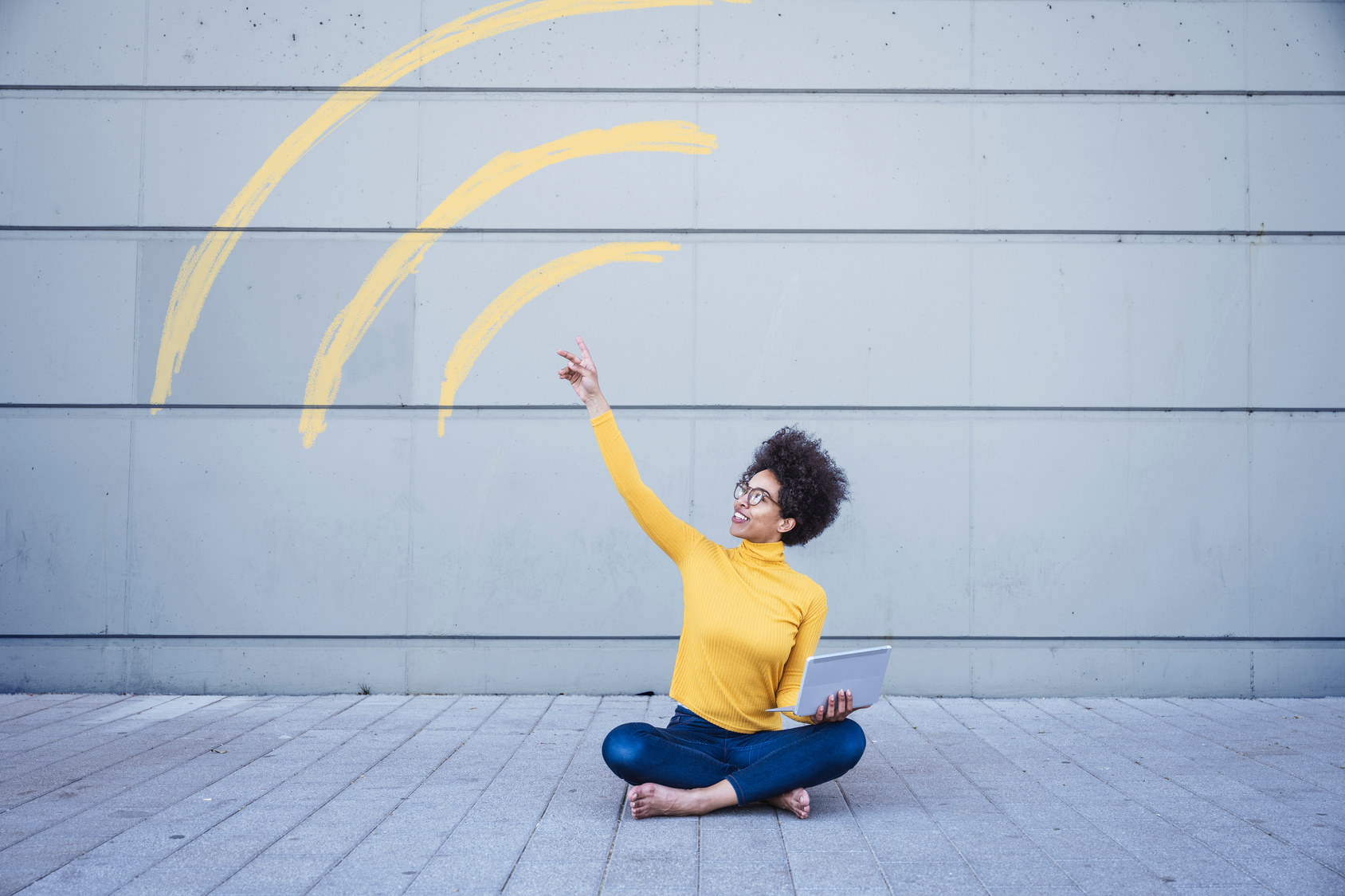 Woman sitting on ground holding laptop connected through WiFi sign