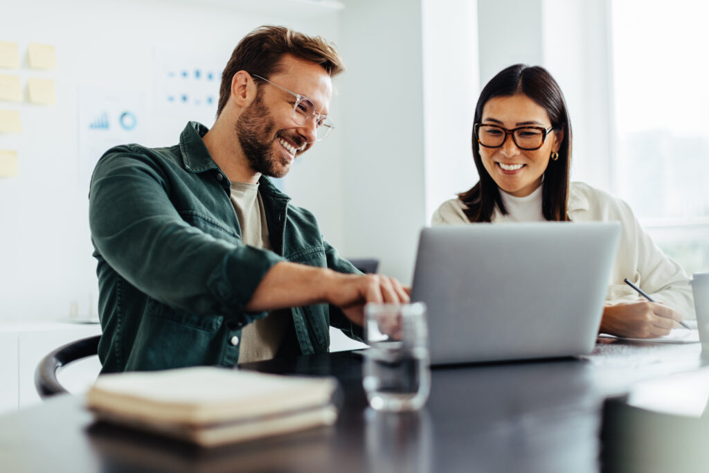 Two young business professionals laughing at table