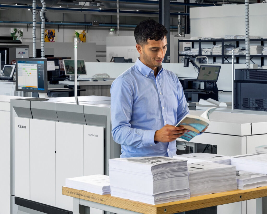 Man in print shop with high speed commercial printer for booklet making