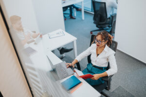 Professional woman at a desk with laptop and notebook in a modern office setting