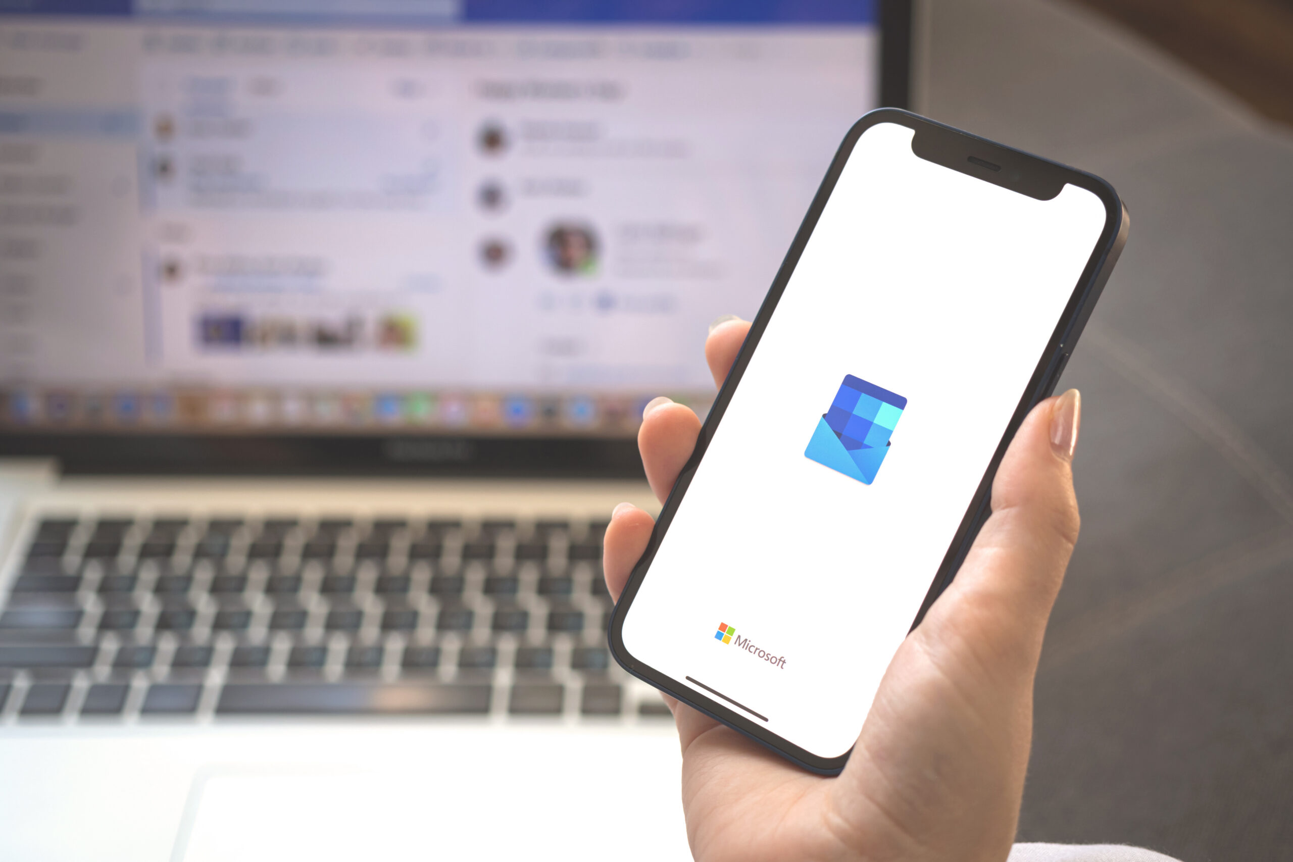 Outlook app logo on mobile phone screen. Woman using Microsoft Outlook application photo