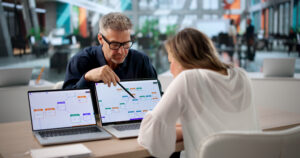 Two Business Professionals Collaborate On Software Workflow Automation Project.